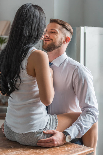back view of woman sitting on table near handsome boyfriend in suit  - Photo, Image
