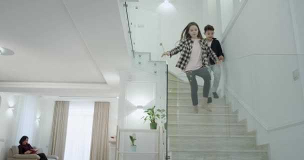 Charismatische kleine jongen en meisje in de ochtend loopt naar de eerste verdieping naar een grote woonkamer gaan ze naar hun moeder en zus om te zeggen goedemorgen en knuffelen mooie elkaar - Video