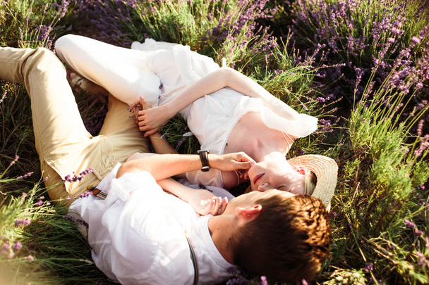 Prachtig portret van de bruid en bruidegom liggend in een Lavendelveld - Foto, afbeelding