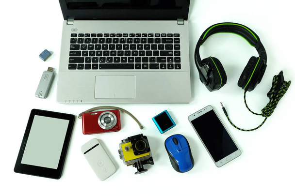 Bureau met gadgets of elektronische apparatuur voor dagelijks gebruik, laptop computer, mobiele telefoons en digitale camera geïsoleerd op witte achtergrond - Foto, afbeelding
