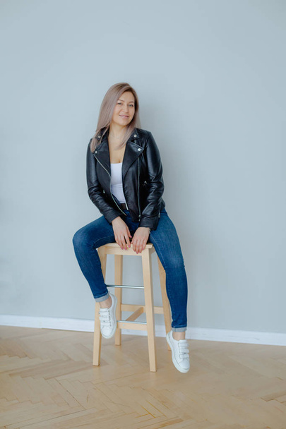 A blonde woman in a black leather jacket is sitting - Φωτογραφία, εικόνα