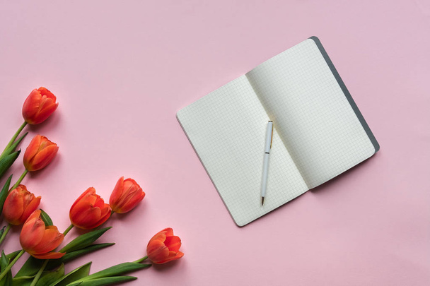 Notebook with cup of tea and red tulips on pink background. Place for your texy - Photo, Image