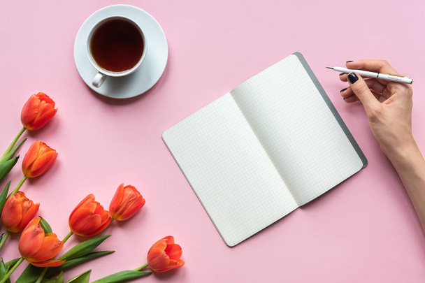 Muistikirja ja tulppaanit vaaleanpunaisella taustalla. Paikka sinun texy
 - Valokuva, kuva