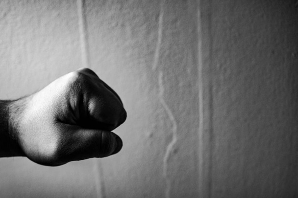 Агрессивный монохромный взрослый мужчина сжал кулак на черном фоне
. - Фото, изображение