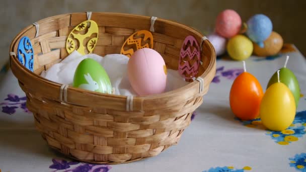Barevná velikonoční vejce zelená, žlutá a růžová v košíku. Mužská ruka přidává jedno růžové a jedno žluté velikonoční vajíčko. - Záběry, video