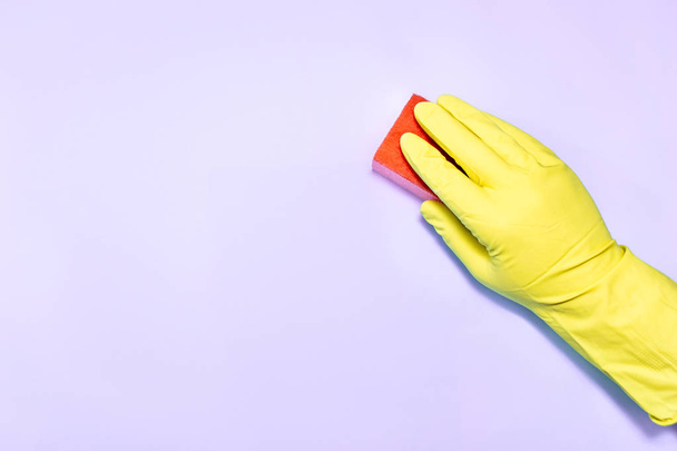 Mężczyzna ręka w rękawiczce z gąbką na fioletowym tle. - Zdjęcie, obraz