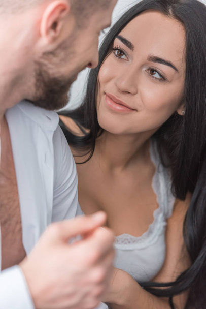 selektivní zaměření přitažlivé bruneté dívky při pohledu na vousatého přítele doma - Fotografie, Obrázek