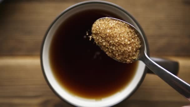 Wlać cukier trzcinowy z łyżki do filiżanki herbaty - Materiał filmowy, wideo