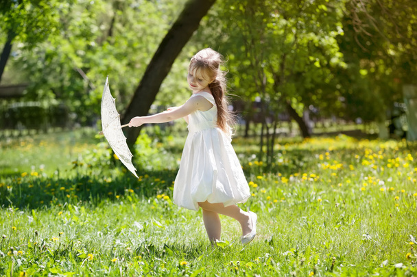 κορίτσι με μια ομπρέλα δαντέλα καλοκαίρι παίζοντας στο πάρκο - Φωτογραφία, εικόνα