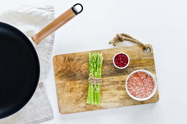 A bunch of mini asparagus on a wooden chopping Board. White background, top view, space for text. - Valokuva, kuva