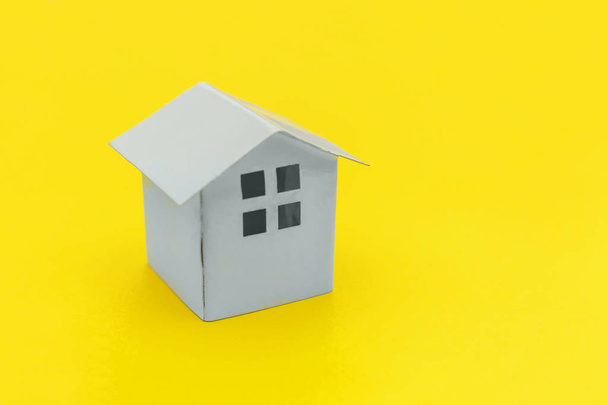 Diseño simple y minimalista con casa de juguete blanco en miniatura aislada sobre un fondo de moda moderno de color amarillo
 - Foto, imagen