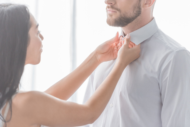 brunette vrouw aanraken kragen van bebaarde man in wit overhemd  - Foto, afbeelding