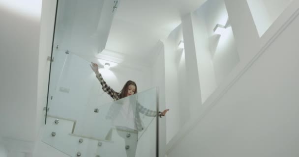 Güzel bir modern evde çok parlak mutlu dokuz yıl kız uzun kıvırcık saç merdivenlerden aşağı çalışan ilk kata o büyük gülümsüyor. 4k - Video, Çekim