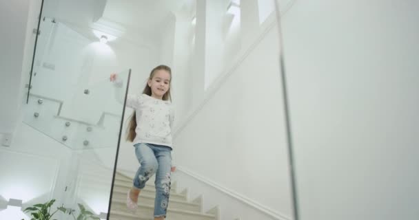 Una niña de seis años de edad por la mañana en una moderna casa de diseño escaleras que bajan al primer piso
. - Metraje, vídeo