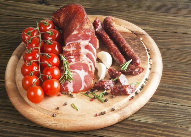 delicious smoked ham on wooden table with rosemary and tomatoes - Photo, image