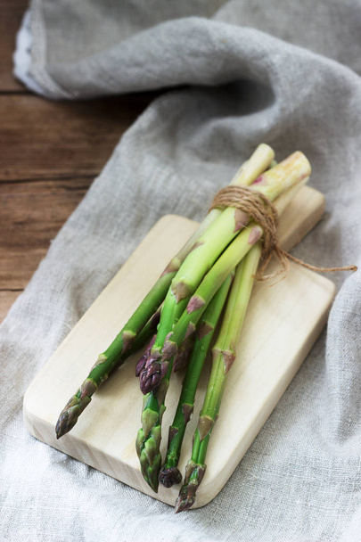A bunch of fresh asparagus, tied with twine, against a linen tablecloth. Rustic style. - Foto, afbeelding
