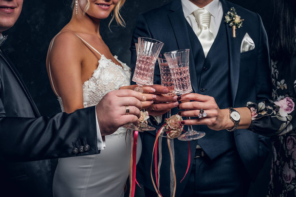 Close-up of bride and groom clinking champagne glasses at a wedding party. - Photo, Image