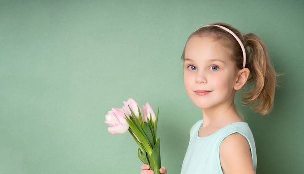 Adorable smiling little girl with tulips - Fotó, kép