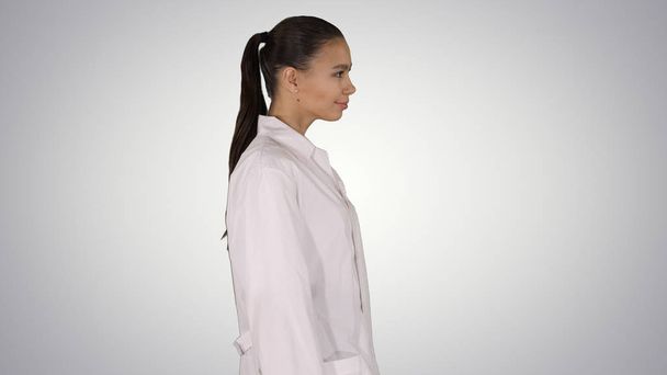 Doctor beautician in a white robe is walking on gradient background. - Foto, imagen