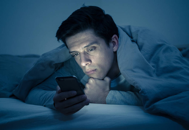 Young mobile phone addict man awake at night in bed using smartphone for chatting, flirting and sending text message. In communication, Internet addiction and Social media network abuse concept - Foto, immagini