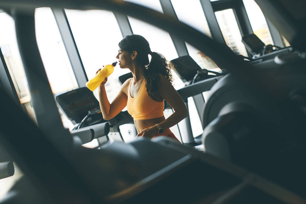 Egészséges nők sárga sport inget ivóvíz az edzőteremben - Fotó, kép