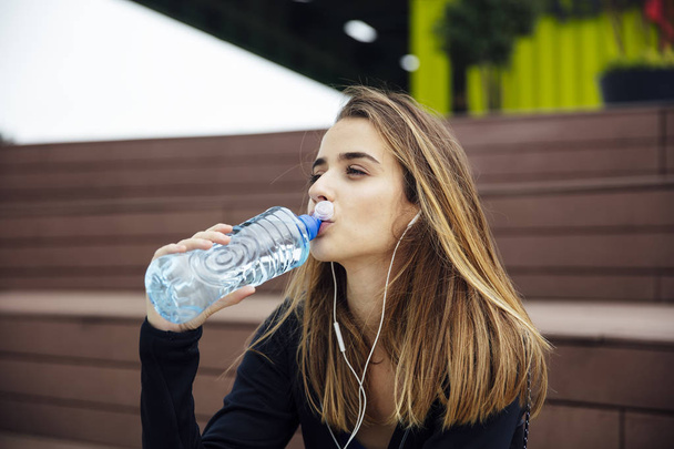 Молоді красиві жінки відпочивають і п'ють воду після вправ на відкритому повітрі
 - Фото, зображення