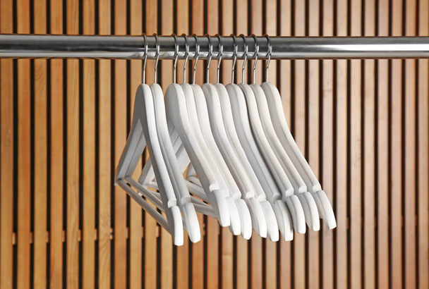 Empty hangers on rail against wooden background - Foto, afbeelding