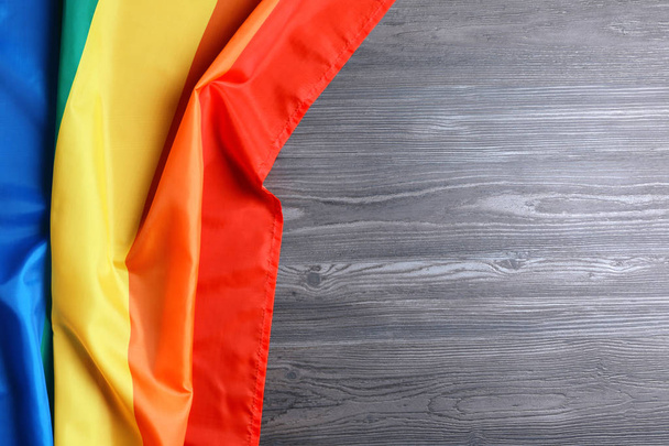Bright rainbow gay flag on wooden background, top view with space for text. LGBT community - Photo, Image