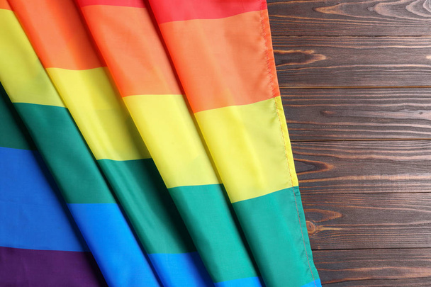 Bright rainbow gay flag on wooden background, top view with space for text. LGBT community - Фото, изображение