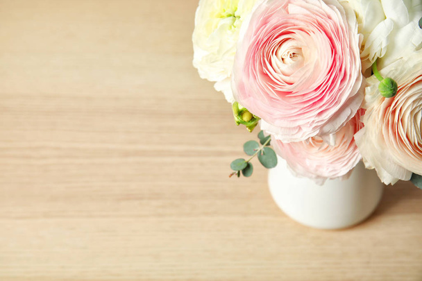 Beautiful spring ranunculus flowers in vase on wooden table. Space for text - Fotó, kép