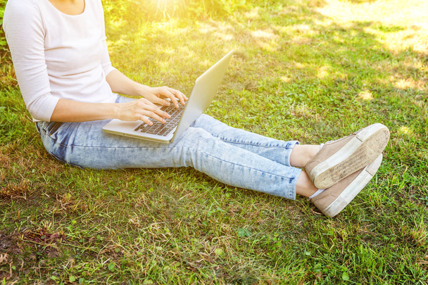 Woman legs on green grass lawn in city park, hands working on laptop pc computer. Freelance business concept - Fotó, kép