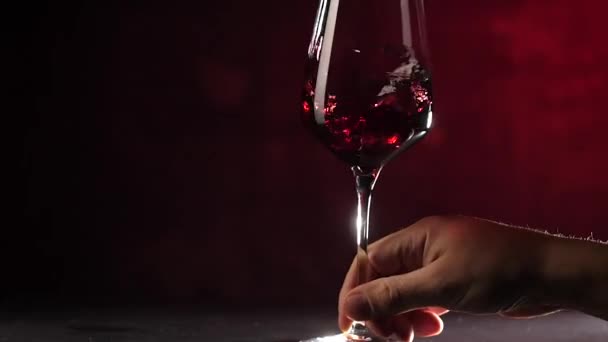 tiro cortado de pessoa agitando vinho tinto em vidro no fundo vermelho escuro
 - Filmagem, Vídeo