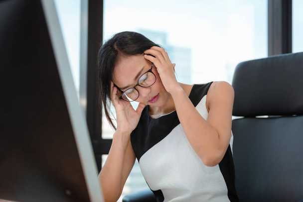 Портрет ділової жінки, що має головний біль під час роботи на робочому місці, азіатка страждає від синдрому втоми офісу. Концепція бізнесу фінансів та охорони
. - Фото, зображення