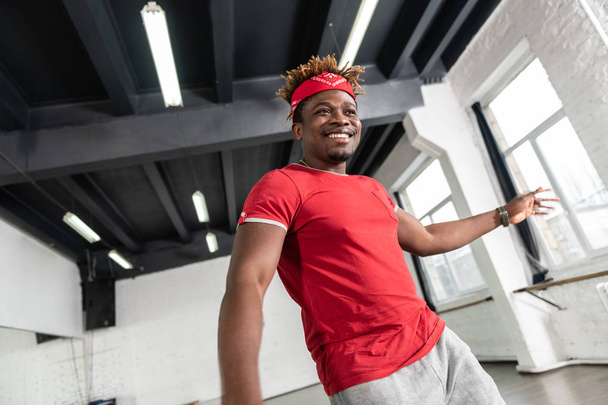 Appealing African American guy in bright t-shirt dancing in studio - Photo, Image