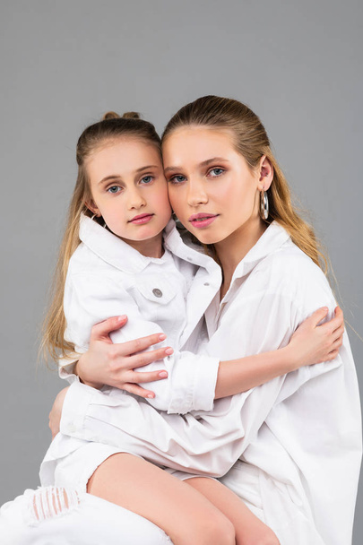 Красивая темноволосая старшая девочка носит свою младшую сестру
 - Фото, изображение