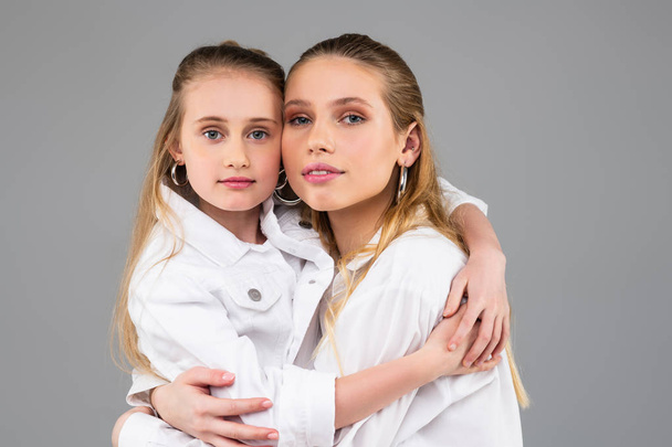 Long-haired young sisters posing together on grey background - Фото, зображення