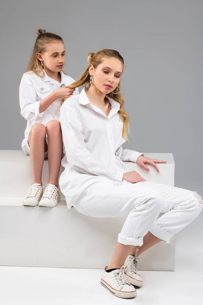 Calm long-haired little girl sitting behind her elder sister - Фото, зображення