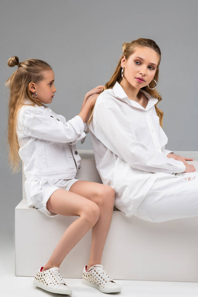 Attentive young kid in white jacket being concentrated on styling hair - 写真・画像