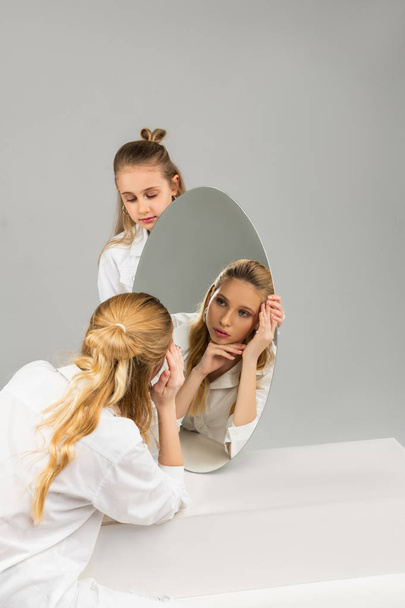Helpful young girl carefully carrying round mirror while her attentive sister - Foto, immagini