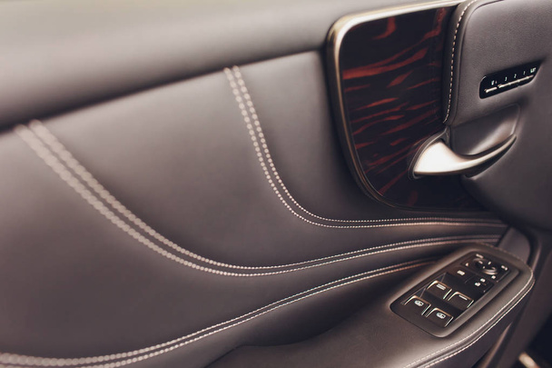 car leather interior details of door handle with windows controls and adjustments. Car window controls. - Foto, Imagem