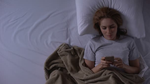 Woman lying in bed and reading bad news message from lover, loneliness, top-view - Footage, Video