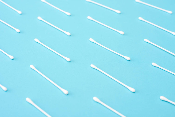 White cotton buds lie in a row on a blue background. - Photo, Image