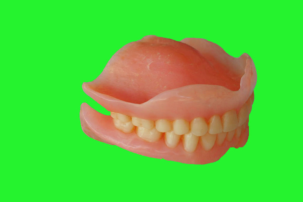 Zubní protézy na zeleném pozadí  - Fotografie, Obrázek