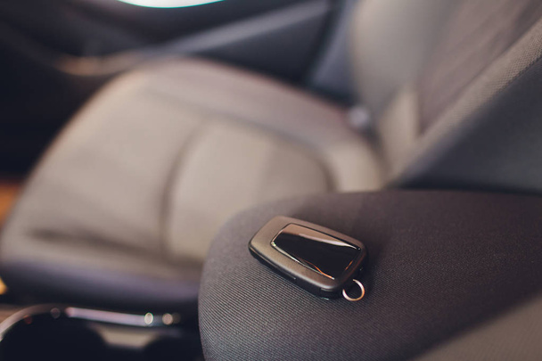 Closeup inside vehicle of wireless key ignition. Start engine key. Car key remote in black perforated leather interior. Modern car background. Modern car Interior details. Car detailing. Keys close up - Foto, Imagem
