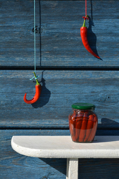 Säilykepurkki hyllyllä ja punainen kuuma chili pippuri käsi seinällä
 - Valokuva, kuva