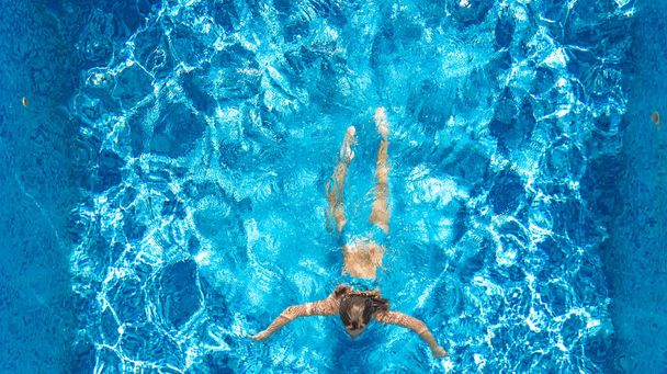 Ενεργό κορίτσι στην πισίνα εναέρια θέα drone από ψηλά, νεαρή γυναίκα κολυμπά σε μπλε νερό, τροπικές διακοπές, διακοπές σε θέρετρο έννοια - Φωτογραφία, εικόνα