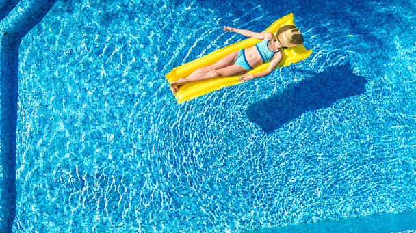 Yüzme havuzunda dinlenen bir kız, şişme yatakta yüzen bir çocuk ve aile tatilinde suda eğlenen bir kız, tropik tatil beldesi, yukarıdan gelen hava aracı manzarası. - Fotoğraf, Görsel