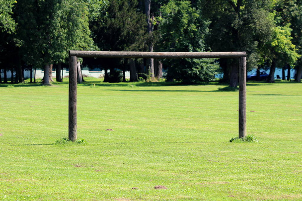 Cíl pro fotbalový trénink vyrobený ze silných dřevěných polic uprostřed čerstvě řezané zelené trávy s velkými lesními stromy v pozadí za teplého slunného dne - Fotografie, Obrázek