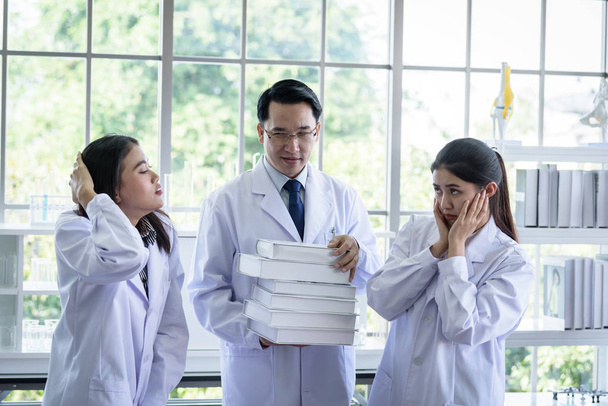 Senior Aziatische wetenschapper heeft het toewijzen van nieuwe baan aan studenten in labo - Foto, afbeelding