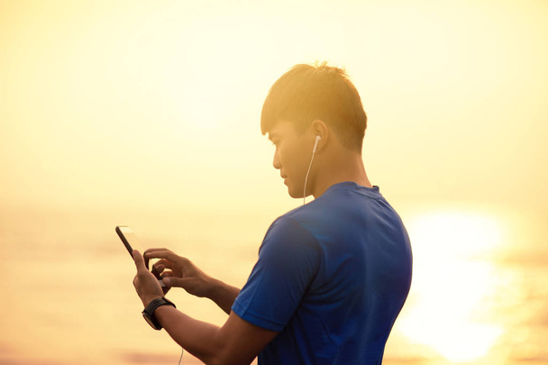 jeune homme courir sur la plage et vérifier cardiofréquencemètre sur sm
 - Photo, image